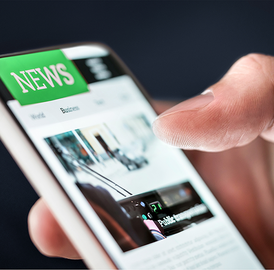 Close-up of a person reading IT and business news on a smartphone, representing RainTech’s media presence and announcements