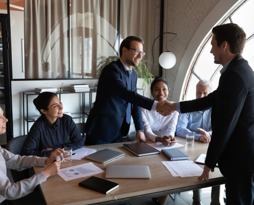 Diverse group of clients thanking professional for help, leader shaking hand on meeting.