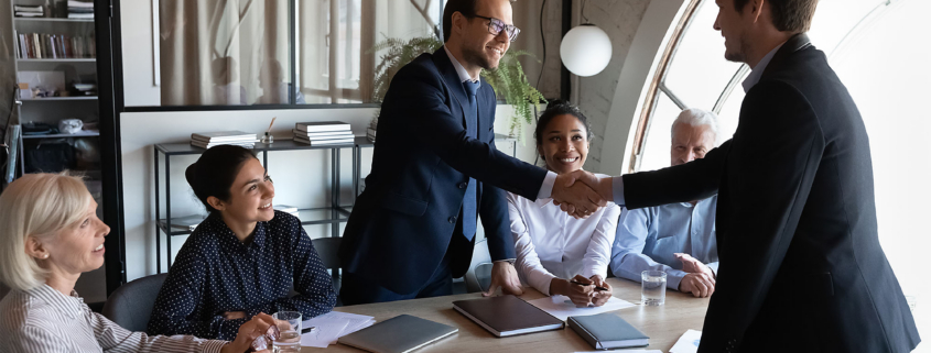 Diverse group of clients thanking professional for help, leader shaking hand on meeting.