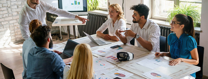 Group of young confident happy business people analyzing data during meeting in the office.